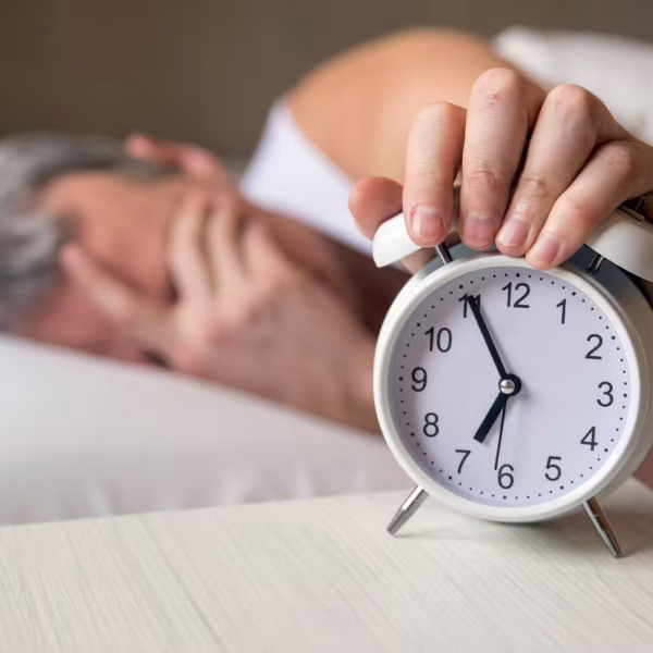 Un homme éteint son réveil le matin après une nuit difficile.